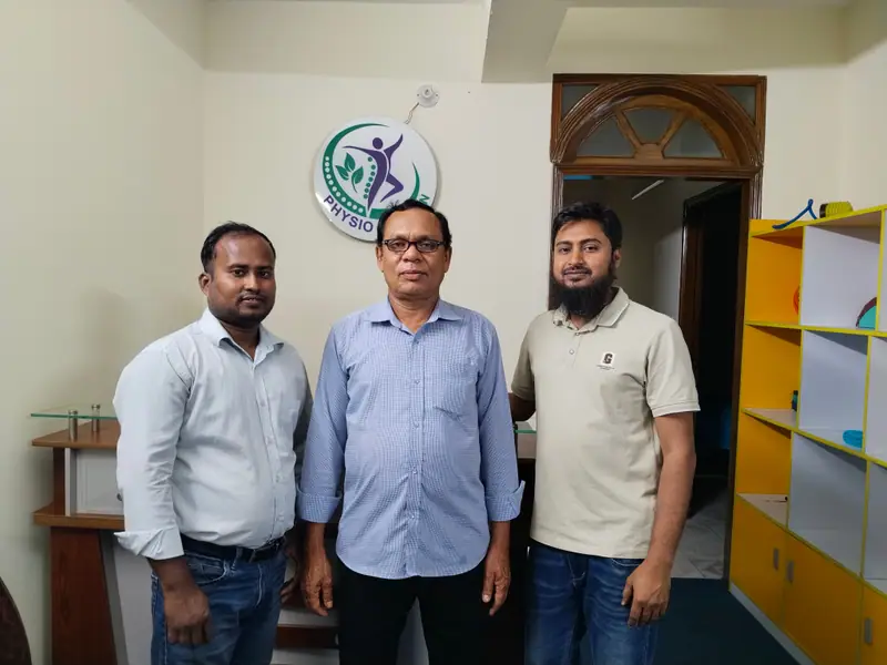 Three men standing together in the reception area of the Physio Motion centre in Uttara