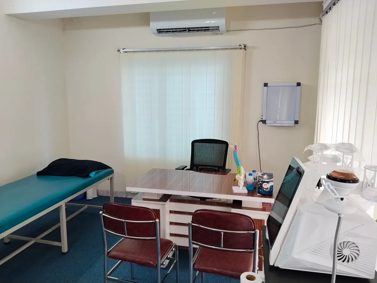 A consultation room at Physio Motion with a teal treatment couch, desk, spine model and therapy equipment